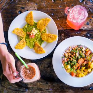 una mesa con dos platos de comida y una bebida en Selina Manuel Antonio, en Manuel Antonio