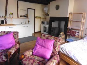 a living room with two chairs and a bed with purple pillows at Le trou dans le mur in Uzerche