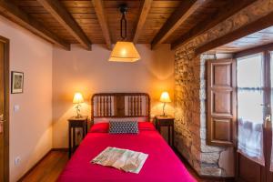 um quarto com uma cama vermelha e 2 candeeiros em Casas Rurales Pandesiertos em Cangas de Onís