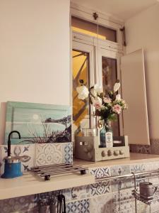a bathroom counter with a mirror and a vase of flowers at B&B Mastro Francesco in Scilla
