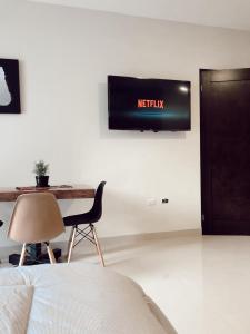 a television on a wall with a chair and a table at Suites Santiago in Santiago