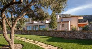 a house with a stone wall and a tree at Agroturismo S'Arboçar in Sant Llorenç des Cardassar