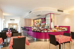 a restaurant with a purple counter with tables and chairs at Augustus Hotel in Biella