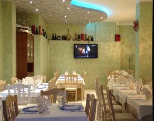 Civale Holidays Apartment في فيتري: غرفة طعام مع طاولات بيضاء وكراسي وتلفزيون