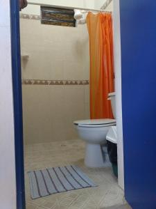 a bathroom with a toilet and an orange shower curtain at Hostal Las Cruces in Valladolid