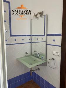 baño con lavabo verde y espejo en HOSPEDERÍA CASTILLO DE ALCAUDETE, en Alcaudete