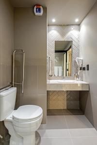 a bathroom with a toilet a sink and a mirror at Slim Curitiba Alto da XV by Slaviero Hotéis in Curitiba