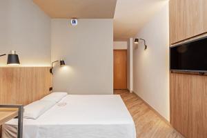 a small room with a bed and a flat screen tv at Slim Curitiba Alto da XV in Curitiba