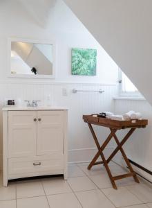 a white bathroom with a sink and a table at Grey Gables Inn in Pembroke