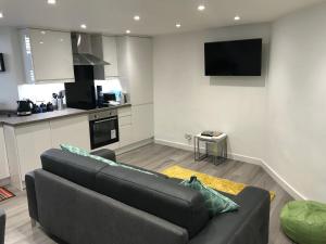 ein Wohnzimmer mit einer schwarzen Couch und einer Küche in der Unterkunft Daisy Cottage in Saint Monance