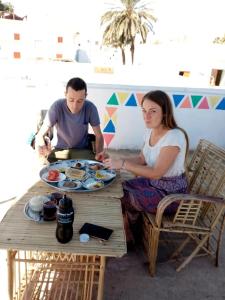 a man and woman sitting at a table with a plate of food at Roma House in Aswan