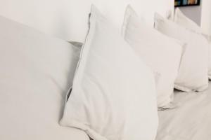 a pile of white pillows on a bed at NIU LUX Apartments in Genoa
