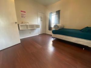 ein leeres Zimmer mit einem Bett und einem Holzboden in der Unterkunft WHOLE Family - WholeVille in Sacramento