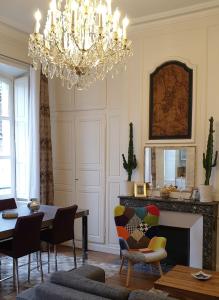 ein Wohnzimmer mit einem Kronleuchter, einem Tisch und Stühlen in der Unterkunft Calme et au cœur du centre historique in Bourges