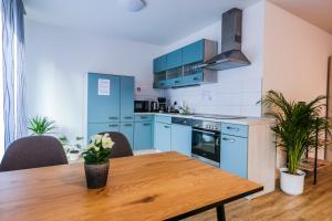 a kitchen with blue cabinets and a wooden table at Hotel Sleep-Station Börnsen bei Hamburg 24H Self Check-in in Börnsen
