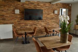 a restaurant with tables and chairs and a tv on a brick wall at LA GLORIETTE in Marche-en-Famenne