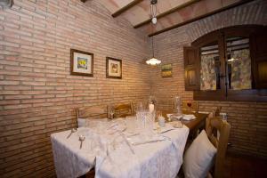 a dining room with white tables and chairs and a brick wall at Casa Rural El Tenado in Aldea de Trujillo +22 photos