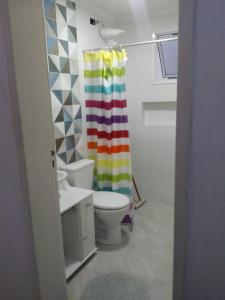 a bathroom with a toilet and a rainbow shower curtain at Riviera Massaguaçu 23 in Caraguatatuba