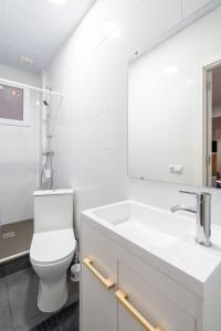 a white bathroom with a toilet and a sink at Jardín Botánico Rooms in Valencia