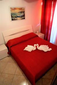 um quarto com uma cama vermelha com duas toalhas em Central House em Realmonte