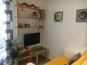 uma sala de estar com uma televisão, um sofá e uma mesa em LA GRACETTE Les Studios em Aix-en-Provence