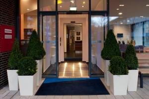 an entrance to a building with potted plants in front of it at Holiday Inn Express Gütersloh by IHG in Gütersloh