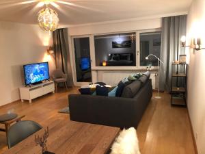 un soggiorno con divano nero e TV di Steinfeldstudio in Rottach Egern a Rottach-Egern