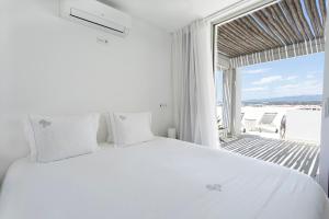 a bedroom with a white bed and a large window at One2Seven in Ferragudo