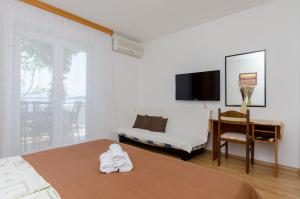 a bedroom with two beds and a desk and a television at Knezovicapartments in Živogošće