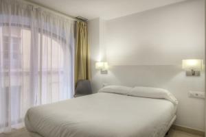 1 dormitorio con cama blanca y ventana en Apartaments Lauria, en Tarragona