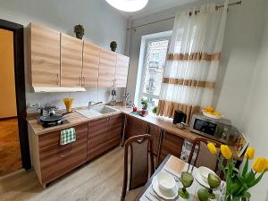 une cuisine avec des placards en bois et une table ornée de fleurs jaunes dans l'établissement Inn Home Apartments in Kiev Center, à Kiev