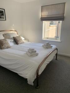 a bedroom with a bed with white sheets and a window at No.10 in Stornoway