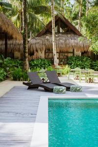 a resort with a pool and chairs and a building at Las Palmas Villas and Casitas Siargao in General Luna