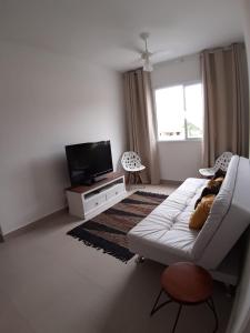 a living room with a white couch and a television at Apartamento Martinica 2 in Caraguatatuba