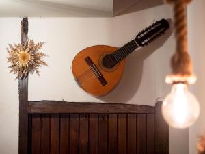 a guitar hanging on a wall next to a wall at CASA RURAL CRUZ - Self check-in in Boltaña