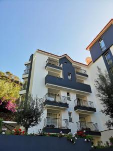 a large white building with balconies and flowers at Santa Cruz Village Hotel in Santa Cruz