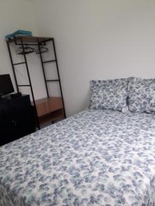 a bedroom with a bed with a blue and white comforter at Apartamento Martinica 2 in Caraguatatuba
