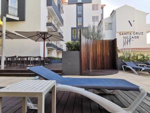 a patio with a bench and a table and an umbrella at Santa Cruz Village Hotel in Santa Cruz