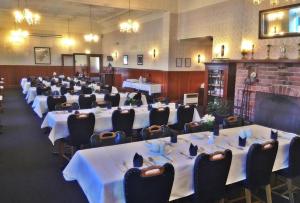 uma sala cheia de mesas e cadeiras com toalha de mesa branca em Leviathan Hotel em Dunedin