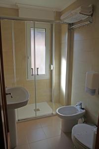 a bathroom with a shower and a toilet and a sink at Hotel Playa de Merón in San Vicente de la Barquera