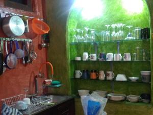 a kitchen with green walls and shelves with cups and utensils at Aylluwasi Guesthouse in Otavalo