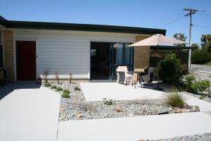 a house with an umbrella and a table and chairs at AHAVA Bed & Breakfast in Waimate