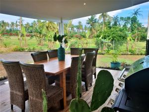 a wooden table and chairs on a deck at Luxury Beachside Home in Maninoa