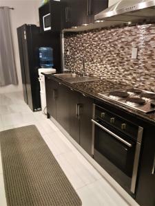 uma cozinha com armários pretos, um lavatório e um fogão em Luxury Beachside Home em Maninoa