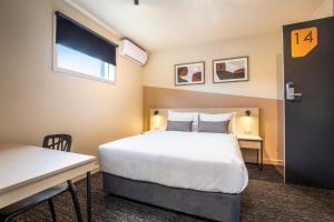 a hotel room with a bed and a table and a desk at Nightcap at Manhattan Hotel in Ringwood