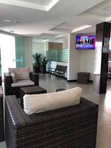 a living room with a couch and a tv on a wall at MIRAGE HOTEL in Porto Seguro