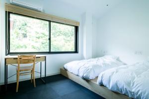 a bedroom with a bed and a desk and a window at Yado Arashiyama in Kyoto