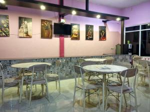 een restaurant met tafels en stoelen en een tv aan de muur bij Hotel Sunset Beach labuhan jukung in Krui