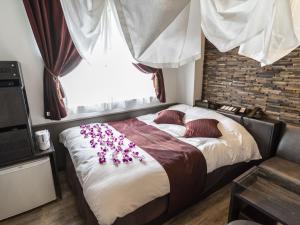 una camera da letto con un letto con fiori rosa di Hotel Petit Bali Garden Shin-Okubo (Adult Only) a Tokyo