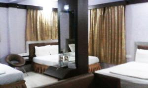 a hotel room with two beds and a mirror at Abimon Residency Kollur in Kollūru